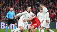 Pemain Portugal, Cristiano Ronaldo, dijaga ketat bek Denmark dalam laga leg pertama perempat final UEFA Nations League 2024/2025 yang digelar di Stadion Parken, Copenhagen, Jumat (21/3/2025) dini hari WIB. (AFP/Jonathan Nackstrand)
