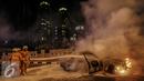 Petugas berusaha memadamkan api mobil yang terbakar di jalan layang Latuharhari, Jakarta, Kamis (18/9/2015). Diduga kebakaran akibat konsleting listrik yang terjadi dibagian depan kap mobil. (Liputan6.com/Faizal Fanani)