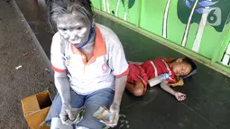 Seorang ibu menghitung uang hasil mengamennya sebagai "Manusia Silver " di salah satu sudut toko di kawasan perempatan Gaplek, Pamulang, Tangerang Selatan, Sabtu (16/1/2021). Ibu tersebut bersama anaknya mendapat penghasilan sekitar 50 ribu per hari sebagai Manusia Silver (merdeka.com/Arie Basuki)