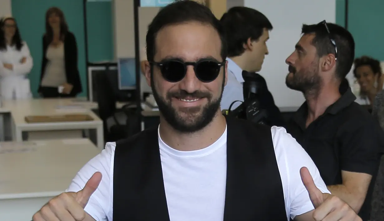 Penyerang baru Juventus, Gonzalo Higuain menyapa awak media saat tiba di Juventus Medical Center, Italia (27/7). Mantan pemain Napoli ini dikontrak Juve selama lima tahun dengan gaji delapan juta euro per musim. (AFP PHOTO/MARCO BERTORELLO)