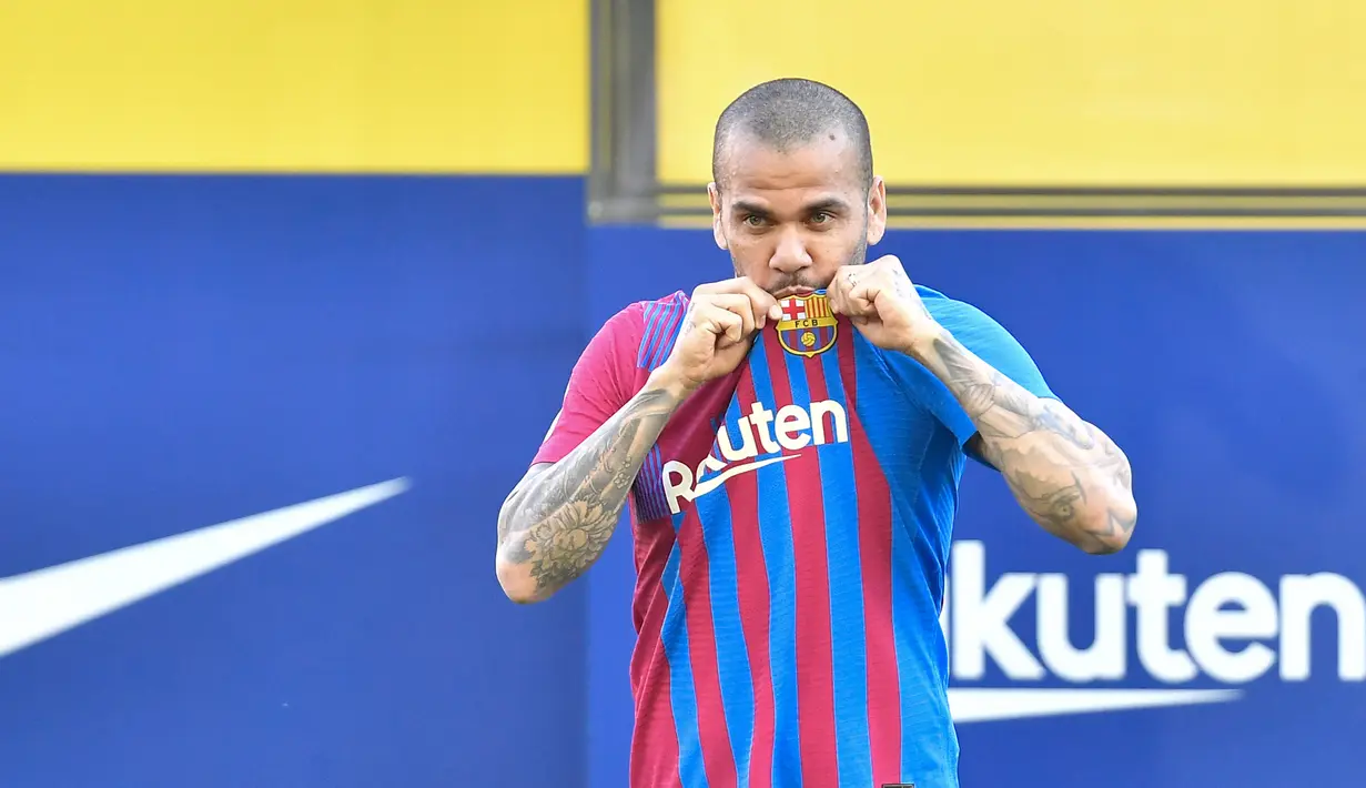 Bek baru Barcelona Dani Alves mencium logo klubnya fans saat menghadiri upacara presentasi di stadion Camp Nou di Barcelona (17/11/2021). Dani Alves mendapatkan sambutan hangat dari sekitar 10 ribu suporter Barcelona yang berada di tribune. (AFP/Pau Barrena)