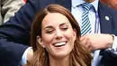 Kate Middleton tertawa saat menyaksikan pertandingan turnamen tenis Wimbledon 2019 di All England Tennis Club di Wimbledon, London, Inggris 2/7/2019). Kate Middleton bergaun gaun putih dari Suzannah dan tas tangan Alexander McQueen dan kacamata hitam Ray-Ban. (AFP Photo/Glyn Kirk)