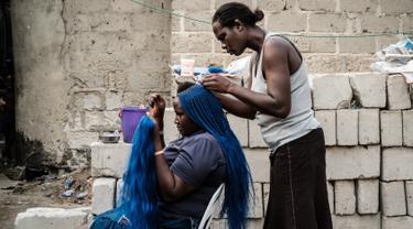 Seorang wanita saat dikepang rambutnya di pemukiman informal Elechi Phase 3 di Port Harcourt, Nigeria selatan (14/2). Nigeria akan mengadakan pemilihan presiden dan parlemen pada tanggal 16 Februari 2019. (AFP Photo/Yasuyoshi Chiba)