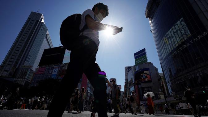 Pria yang memakai masker untuk mencegah penyebaran COVID-19 meyeberang jalan di Shibuya, Tokyo, Jepang, Jumat (3/7/2020). Jepang mengangkat darurat pandemi selama tujuh minggu pada akhir Mei, sebagian besar kegiatan sosial dan bisnis sejak itu telah kembali dimulai. (AP Photo/Eugene Hoshiko)