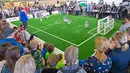 Sejumlah orang menonton pertandingan sepak bola antar tim robot 'Nomadz' dari Swiss melawan robot tim 'Hulk' dari Jerman dalam pertandingan Liga Platform Standar di RoboCup GermanOpen 2018, Magdeburg, Jerman (28/4). (AP/Jens Meyer)