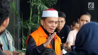 Tersangka Gubernur Aceh Irwandi Yusuf menjawab pertanyaan wartawan usai menjalani pemeriksaan di Gedung KPK, Jakarta, Kamis (26/7). Irwandi Yusuf memakai rompi tahanan dan kopiah merah putih. (Merdeka.com/Dwi Narwoko)