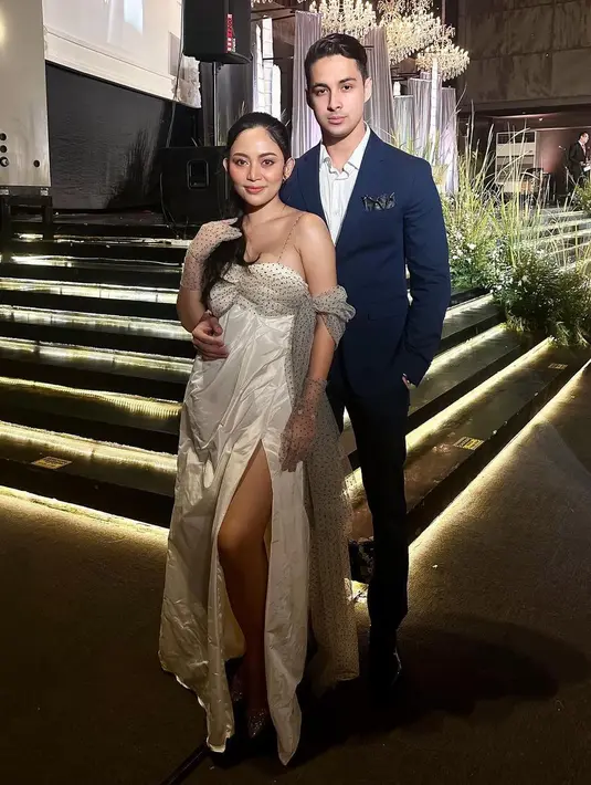 Ini adalah momen keduanya menghadiri pernikahan sahabat Rachel. Berpose berdua, Rachel dibalut strappy dress bernuansa putih. Dress ini memiliki detail cape dan gloves yang serasi, serta high slit. Sedangkan Salim tampil dengan setelan jas dan celana berwarna biru yang serasi, serta kemeja putih. Foto: Instagram.