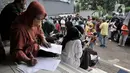 Warga mengisi data di luar gedung Kantor Suku Dinas Dukcapil Jakarta Timur, Senin (15/6/2020). Layanan tatap muka Dukcapil Jakarta Timur yang kembali dibuka sejak Jumat (12/6) lalu disambut antusias warga yang ingin mengurus dokumen administrasi kependudukan. (merdeka.com/ Iqbal S Nugroho)