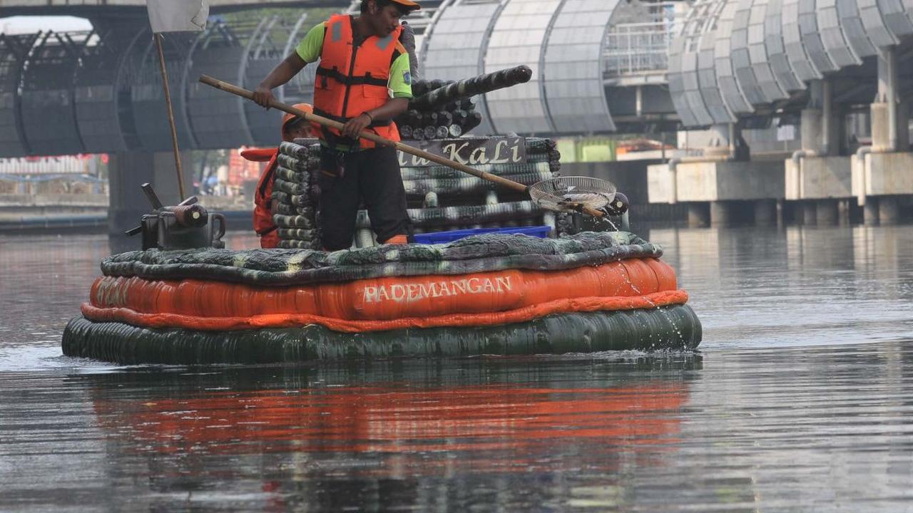 Petugas Unit Penanganan Sampah (UPS) Badan Air Dinas Lingkungan Hidup DKI Jakarta mengambil sampah menggunakan perahu yang terbuat dari sampah botol plastik di aliran Kali Ancol, Jalan Martadinata, Jakarta Utara, Rabu (22/5/2024). Petugas UPS Badan Air me