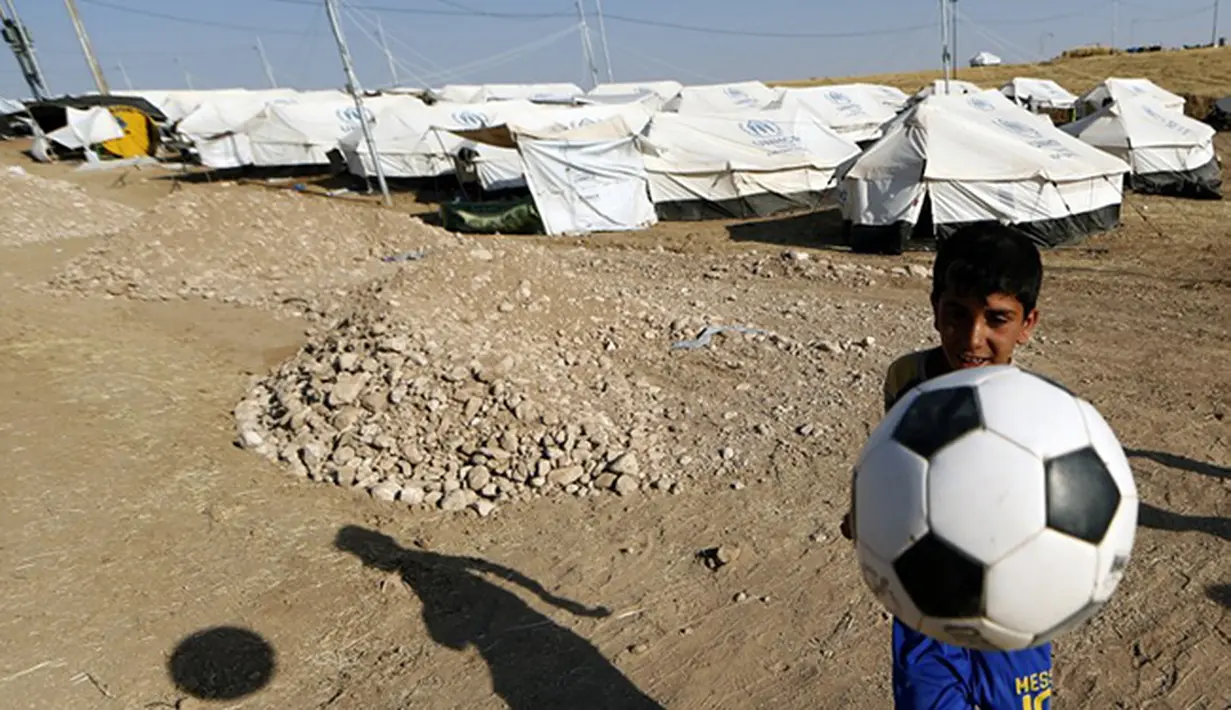 Bocah Sihite asal Irak bermain sepak bola. (AFP PHOTO/KARIM SAHIB)