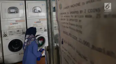 Seorang ibu rumah tangga menaruh cucian di sebuah laundry koin di Jakarta, Sabtu (8/6). Pada libur Lebaran, jasa laundry ramai didatangi konsumen, terutama oleh mereka yang ditinggal mudik asisten rumah tangganya. (merdeka.com/Imam Buhori)