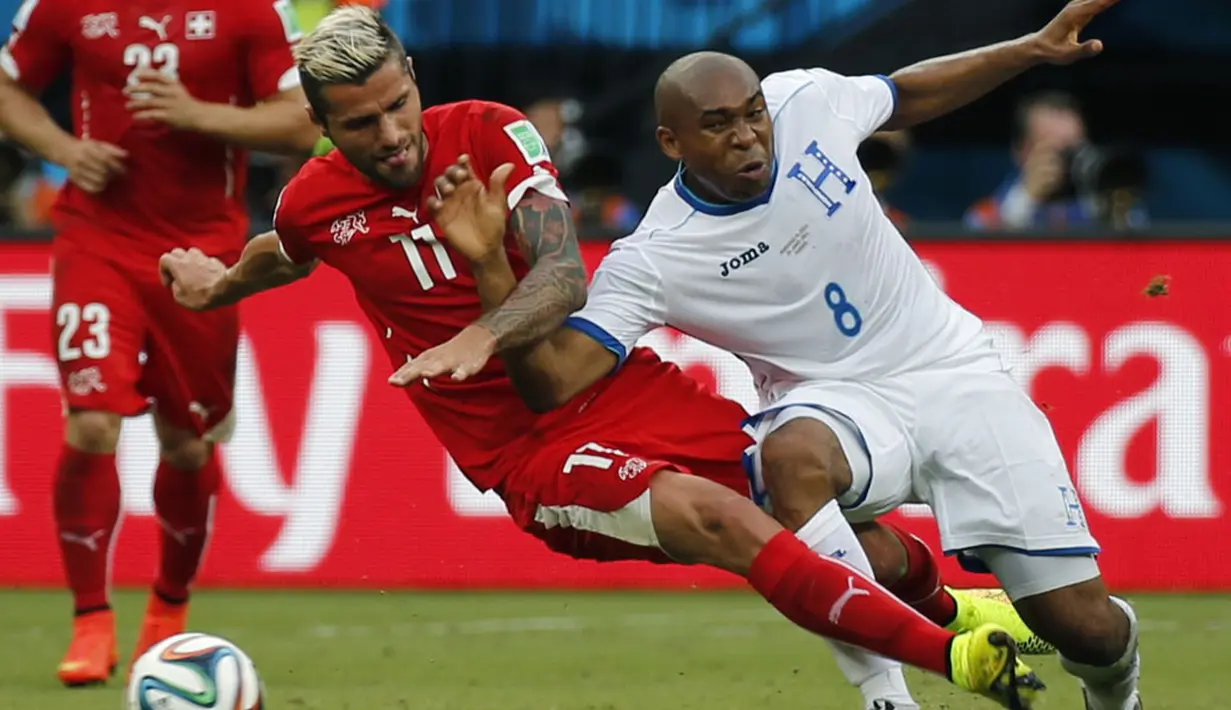 Gelandang Swiss, Valon Behrami (kiri) berusaha menahan pergerakan pemain Honduras, Wilson Palacios, saat berlaga di penyisihan Piala Dunia 2014 Grup E di Stadion Amazonia, Manaus, Brasil, (26/6/2014). (REUTERS/Siphiwe Sibeko)