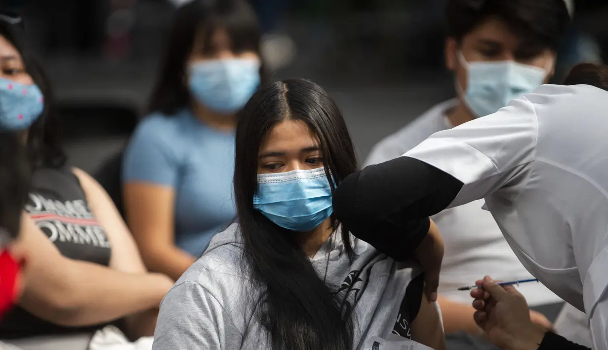 Seorang perawat menginokulasi seorang remaja wanita dengan dosis booster vaksin Pfizer melawan COVID-19 di Mexico City (9/2/2022). Menteri kesehatan Meksiko melaporkan 9.242 kasus baru COVID-19 dan 206 kematian pada Senin (7/2/2022). (AFP/Claudio Cruz)