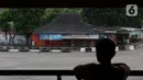 Seseorang melihat-lihat area parkir bus Antar Kota Antar Provinsi di Terminal Kampung Rambutan, Jakarta, Sabtu (25/4/2020). Untuk mencegah dan memutus mata rantai penularan virus Covid-19, pemerintah resmi melarang aktivitas mudik pada Jumat (24/4) lalu. (Liputan6.com/Helmi Fithriansyah)