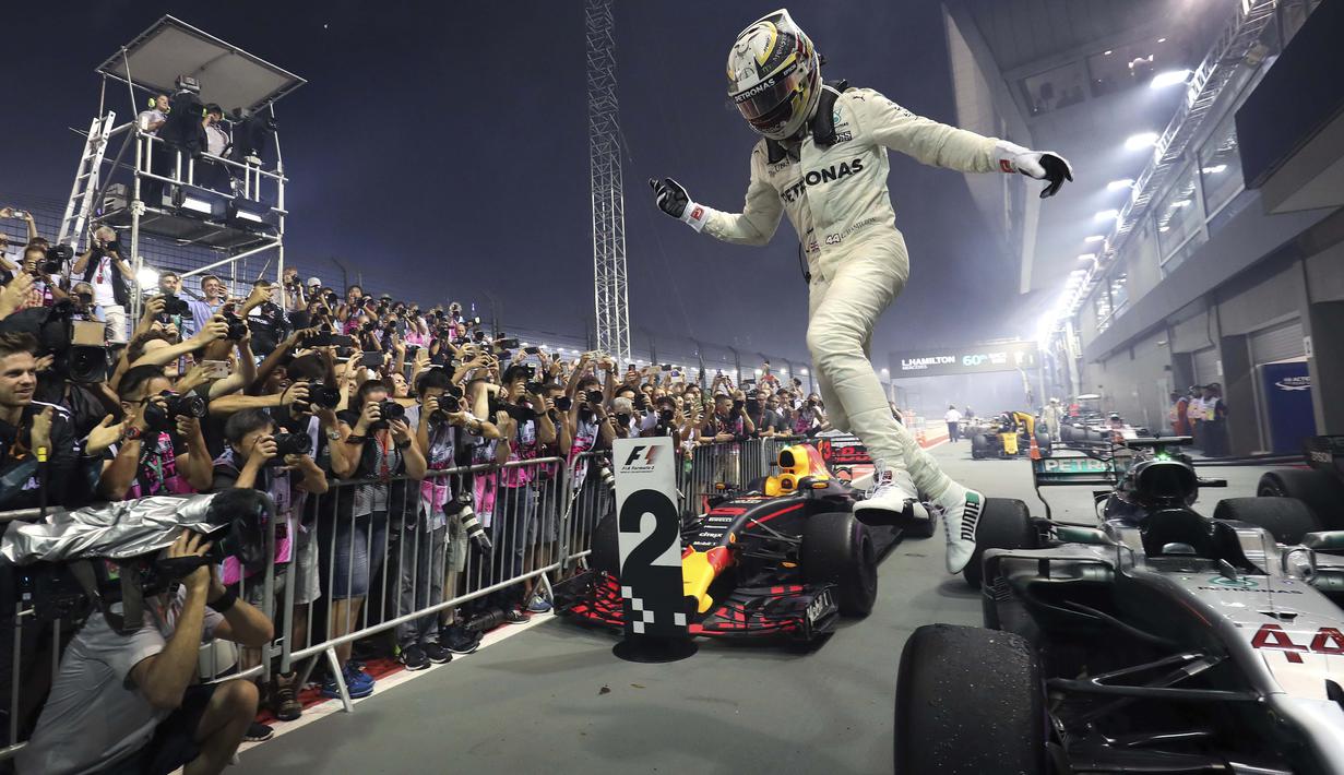 Pebalap Mercedes, Lewis Hamilton merayakan kemenangan saat menjuarai F1 Singapura di  Marina Bay City Circuit, (17/9/2017).  (AP/Yong Teck Lim)