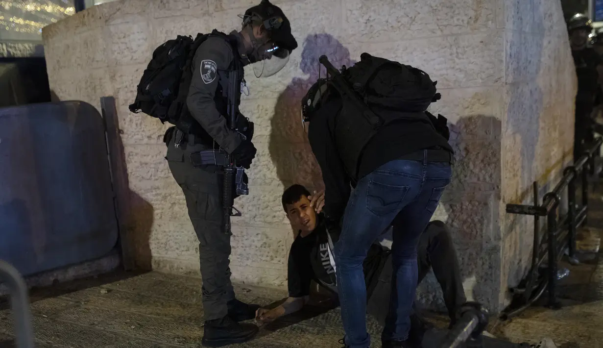 Polisi Israel menahan pemuda Palestina di Gerbang Damaskus ke Kota Tua Yerusalem di kompleks Masjid Al-Aqsa (7/6/2021). Layanan ambulans Bulan Sabit Merah Palestina mengatakan 88 orang Palestina yang terluka dibawa ke rumah sakit setelah terkena peluru logam berlapis karet. (AP Photo/Mahmoud Illean)