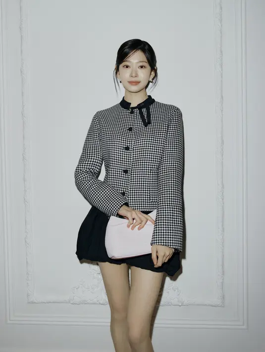 Kim Minju tampil manis dengan blazer kotak-kotak yang dipadu dengan mini skirt balon hitam. Dior Bow Bag soft pink jadi sentuhan feminin pada penampilannya [Dior]