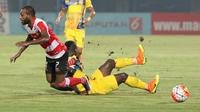 Pemain Madura United, Engelberd Sani (kiri) dihadangan pemain Persiba Balikpapan, Dirkir Gohn Glay pada laga Torabika SC 2016 di Stadion Gelora Bangkalan, Senin(13/6/2016).  (Bola.com/Nicklas Hanoatubun)