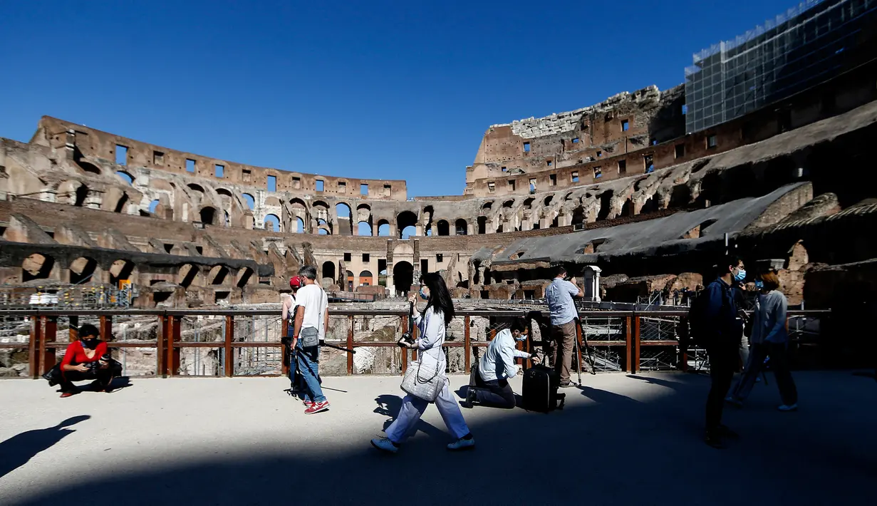 Awak media berjalan di dalam bangunan kuno Colosseum saat pratinjau pers untuk pembukaan kembali di Roma, Italia, Senin (1/6/2020). Monumen Colosseum yang ditutup sejak 8 Maret 2020, telah dibuka kembali dengan beberapa pembatasan akses bagi pengunjung. (Cecilia Fabiano/LaPresse via AP)