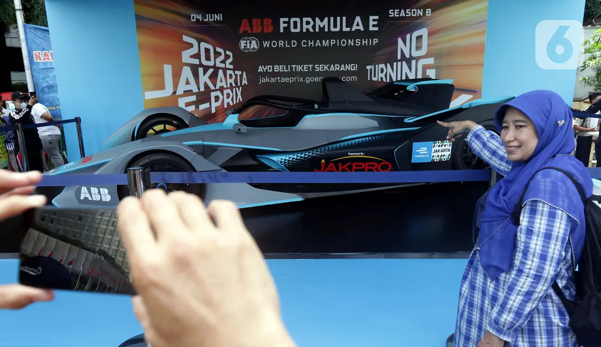 Warga berfoto dengan latar replika mobil Formula E yang dipamerkan di Kawasan Bundaran Hotel Indonesia, Jakarta, Minggu (29/5/2022). Replika mobil balap ramah lingkungan ini dipamerkan untuk mengkampanyekan perhelatan Formula E yang akan digelar 4 Juni mendatang. (Liputan6.com/Helmi Fithriansyah)
