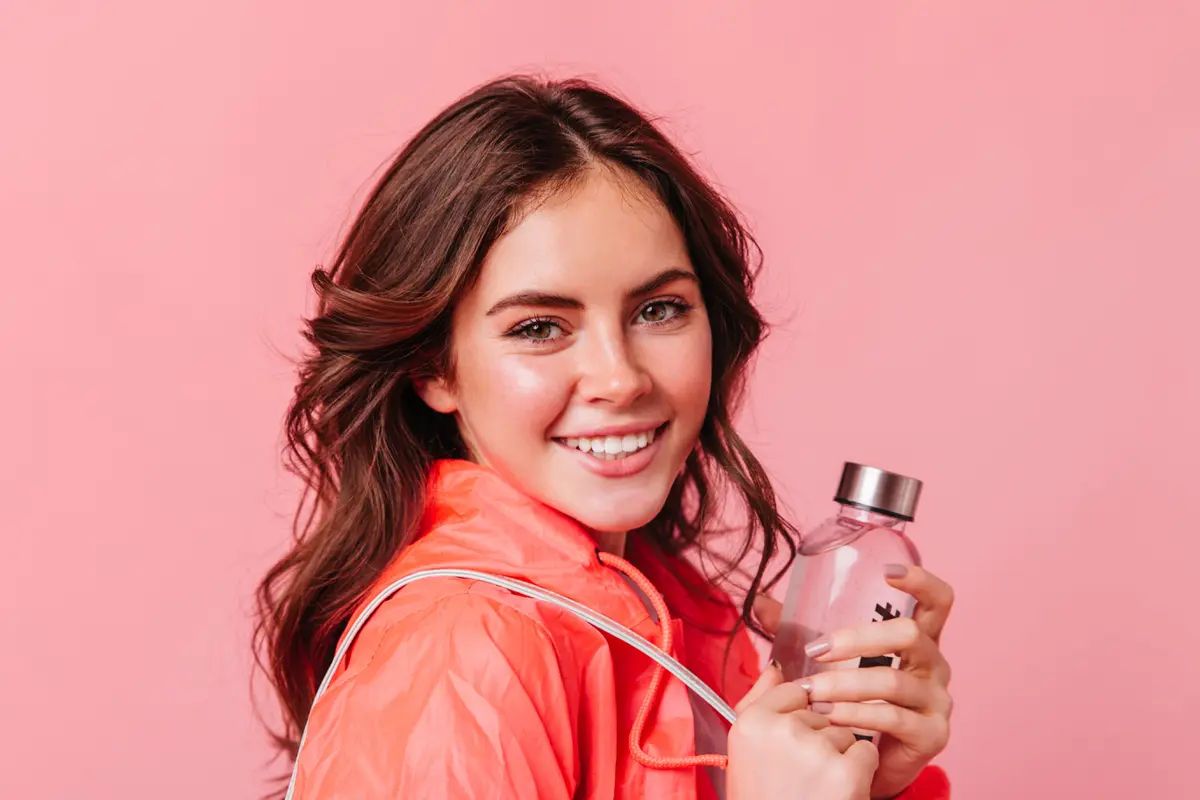 Seorang perempuan sedang menggenggam sebuah botol parfum (Foto Dok: Freepik/lookstudio)