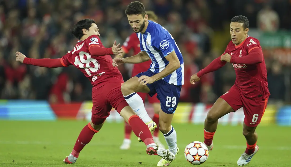 Penyerang FC Porto Joao Mario berebut bola dengan pemain Liverpool, Thiago Takumi Minamino pada pertandingan kelima Grup B Liga Champions di Anfield, Kamis (25/11/2021) dini hari WIB. Kemenangan Liverpool atas Porto dipersembahkan oleh gol Thiago Alcantara dan Mohamed Salah. (AP Photo/Jon Super)
