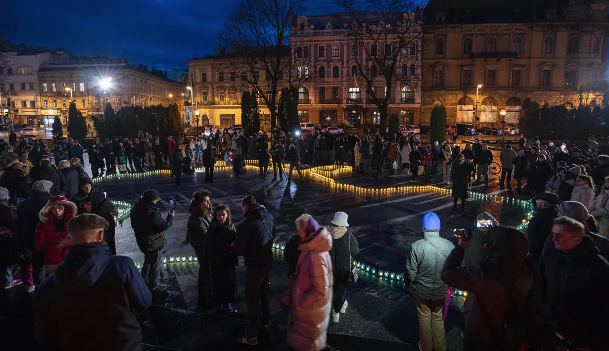 Orang-orang menyalakan lilin membentuk peta Ukraina, untuk mengenang nyawa yang hilang, di depan monumen Taras Shevchenko, di Lviv, Ukraina barat, Selasa malam (5/4/2022). Orang-orang Ukraina berkumpul untuk momen menghormati nyawa yang hilang dalam perang. (AP Photo/Nariman El- Mofty)
