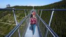 Pengunjung melintasi jembatan gantung untuk pejalan kaki yang merupakan konstruksi terpanjang di dunia setelah pembukaan resminya di sebuah resor pegunungan di Dolni Morava, Republik Ceko, Jumat (13/5/2022). Jembatan sepanjang 721 meter (2.365 kaki) dibangun pada ketinggian lebih dari 1.100 meter di atas permukaan laut. (AP Photo/Petr David Josek)