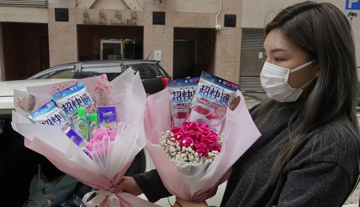 Pemilik toko bunga Iris Leung memberikan bunga dengan masker kepada pembeli pada Hari Valentine di Hong Kong, Jumat (14/2/2020). China  melaporkan peningkatan tajam dalam jumlah orang yang terinfeksi virus baru, ketika jumlah korban mendekati 1.400. (AP Photo/Vincent Yu)