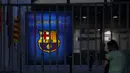 Seorang penggemar mengintip melalui pagar pintu masuk kantor Barcelona di stadion Camp Nou di Barcelona, Spanyol, Kamis (5/8/2021). Messi sudah berstatus tanpa klub sejak tanggal 1 Juli 2021 mengingat kontraknya bersama Barcelona usai. (AP Photo/Joan Monfort)