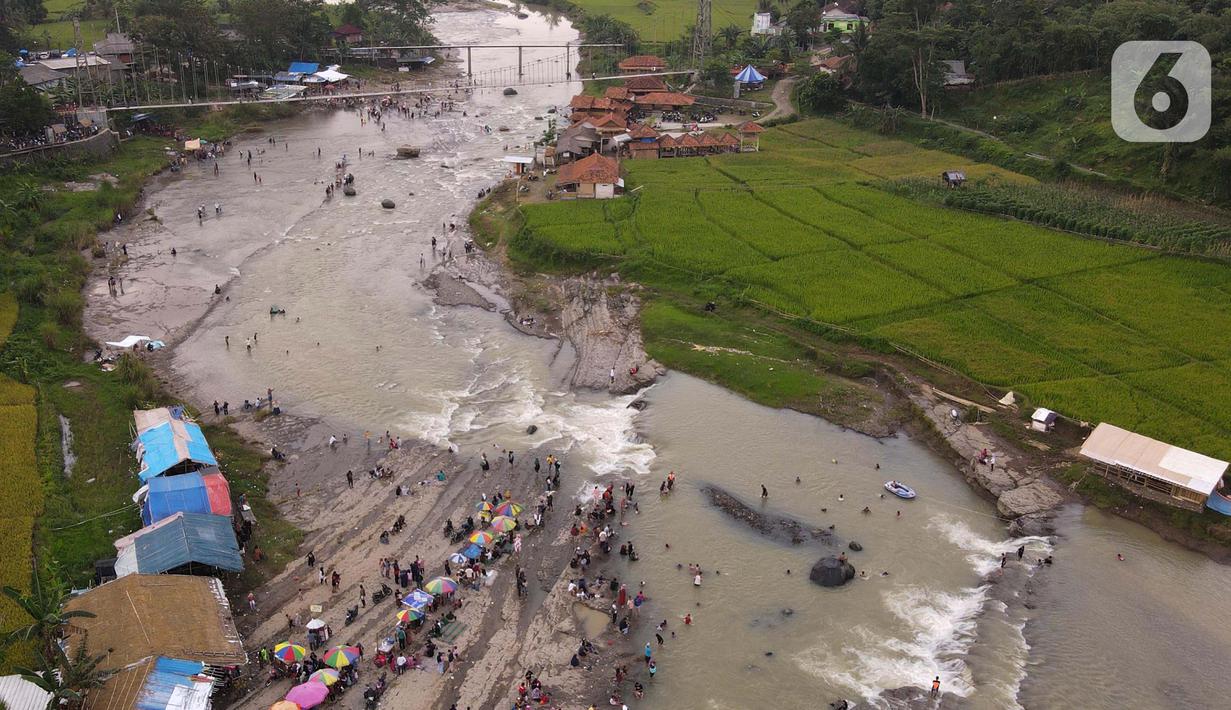<p>Foto udara menunjukkan wisatawan berenang di aliran sungai Cipamingkis Kecamatan Sukamakmur, kabupaten Bogor, Jawa Barat, Kamis (5/5/2022). Warga memanfaatkan aliran sungai tersebut sebagai sarana hiburan Hari Raya Idul Fitri 1443 Hijriah. (merdeka.com/Imam Buhori)</p>