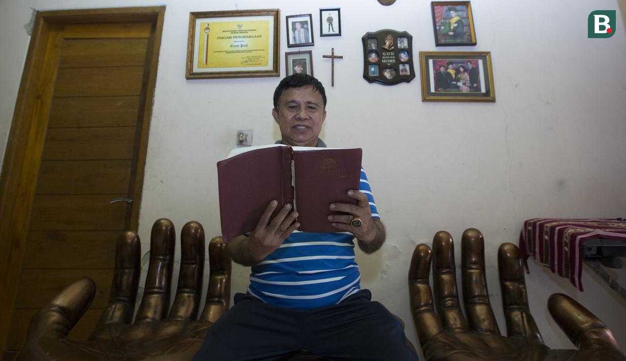 Legenda tinju Indonesia, Ellyas Pical, membaca Alkitab di Kawasan Bintaro, Jumat (13/7/2018). Ellyas Pical adalah petinju Indonesia pertama yang berhasil menjadi juara dunia. (Bola.com/M Iqbal Ichsan)