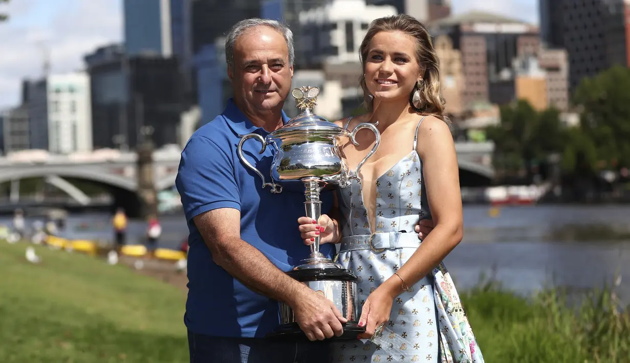 Petenis asal AS Sofia Kenin dan ayahnya Alex berpose dengan trofi Australia Terbuka 2020 setelah kemenangannya atas Garbine Muguruza dari Spanyol di final selama pemotretan di Sungai Yarra, Melbourne, Australia, Minggu, (2/2/2020). (AP Photo/Dita Alangkara)
