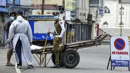 Aparat kepolisian memeriksa seorang warga yang tetap beraktivitas di luar rumah selama penerapan lockdown di Kolombo, Sri Lanka, Sabtu (21/8/2021). Rata-rata kasus harian Covid-19 di Sri Lanka kini mencapai 4.792 orang, melonjak lebih dari dua kali lipat dalam sebulan terakhir. (AFP/Ishara S. Kodika