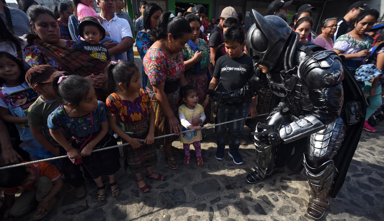 Anggota Saturno Club mengenakan kostum Batman menyapa anak-anak selama parade Dance of Costumes tahunan di sepanjang jalan kota Sumpango, Guatemala, Senin (30/12/2019). Parade kostum yang menampilkan karakter televisi dan film ini untuk memeriahkan malam pergantian tahun. (ORLANDO ESTRADA/AFP)