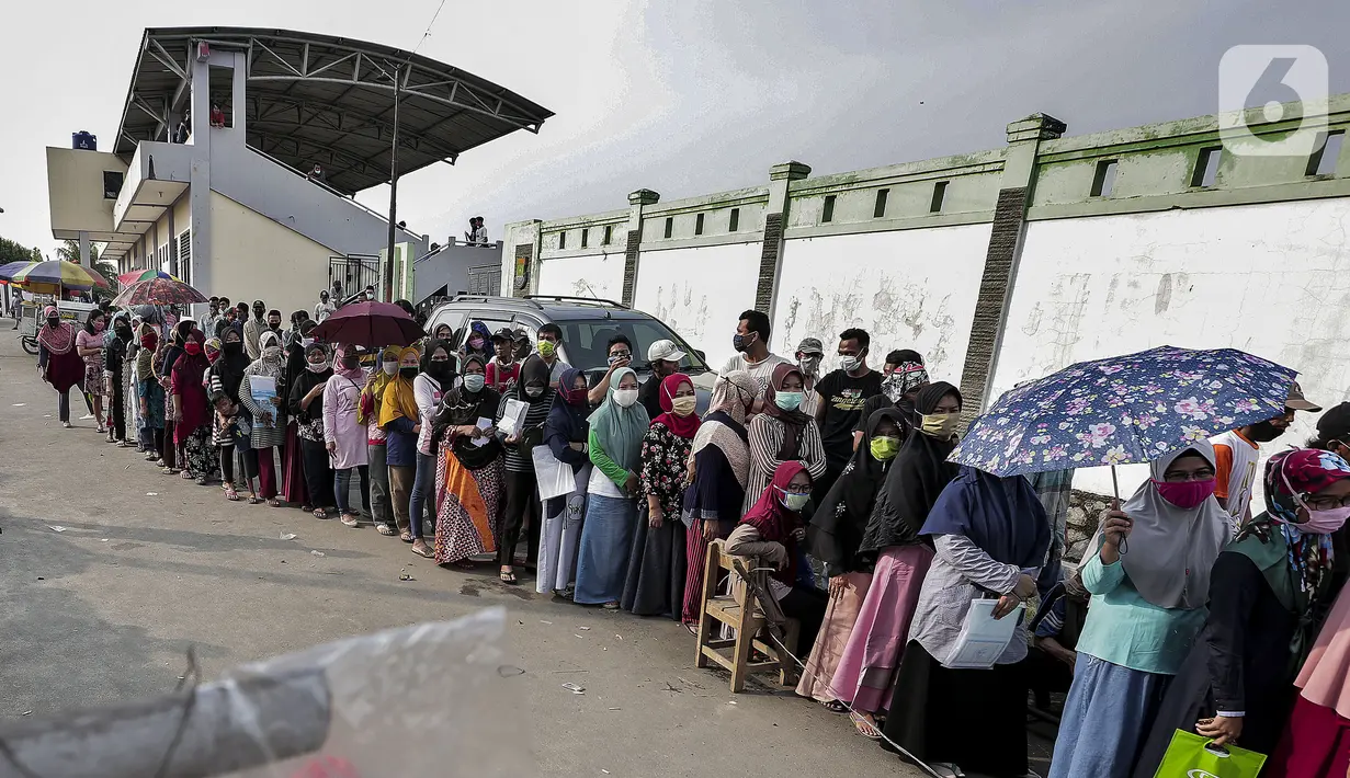 Warga antre untuk menerima Bantuan Sosial Tunai (BST) di Desa Cikande, Kecamatan Jayanti, Kabupaten Tangerang, Banten, Selasa (23/6/2020). Bantuan sebesar Rp 600 ribu per keluarga tersebut diharapkan bisa dimanfaatkan untuk membeli kebutuhan mendesak. (Liputan6.com/Johan Tallo)