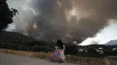 <p>Seorang perempuan menyaksikan api meluas di dekat daerah perumahan di Alhaurin de la Torre, Malaga, Spanyol, Sabtu (16/7/2022). Kebakaran hutan terus menyebar ke seluruh Spanyol ketika petugas pemadam kebakaran bekerja untuk mengendalikan api. (AP Photo/Gregorio Marrero)</p>