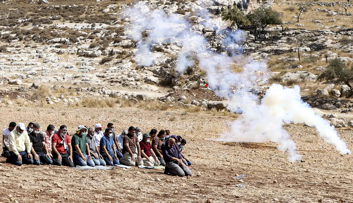 Pengunjuk rasa Palestina melaksanakan salat di tengah tembakan gas air mata oleh tentara Israel di dekat desa Beit Dajan, timur Nablus, Palestina (9/10/2020). (AFP/Jaafar Ashtiyeh)