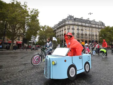 Seorang wanita mengemudikan sepeda yang dihias dengan kardus berbentuk mobil di Place de la Bastille, Paris, Prancis (1/10). Acara hari bebas kendaraan bermotor di Paris ini telah di gelar ketiga kalinya. (AFP Photo/Eric Feferberg)