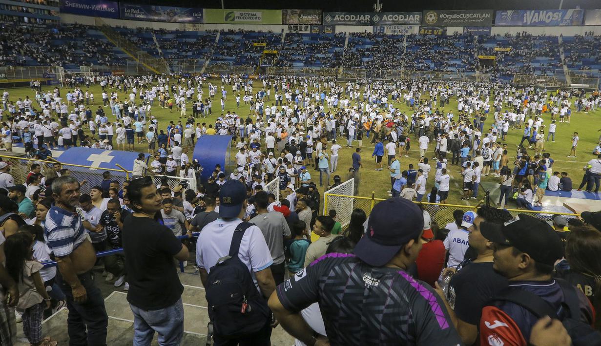 Para suporter berhamburan ke dalam lapangan saat terjadi kerusuhan suporter akibat saling berebut masuk ke dalam Stadion Monumental, Cuscatlan, San Salvador, El Salvador, Sabtu (21/5/2023) waktu setempat untuk menyaksikan laga perempatfinal Divisi Utama El Salvador antara Alianza FC menghadapi Deportivo FAS. (AP Photo/Milton Flores)