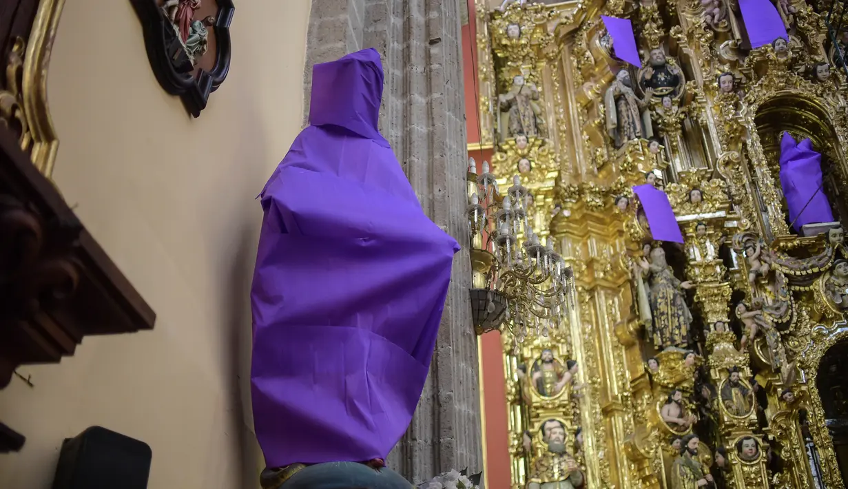 Patung perempuan ditutupi dengan kain ungu di Gereja De los Santos Cosme y Damian di Mexico City, pada Rabu (4/3/2020). Penutupan patung tersebut sebagai bentuk protes terhadap kekerasan gender. (Photo by Pedro PARDO / AFP)