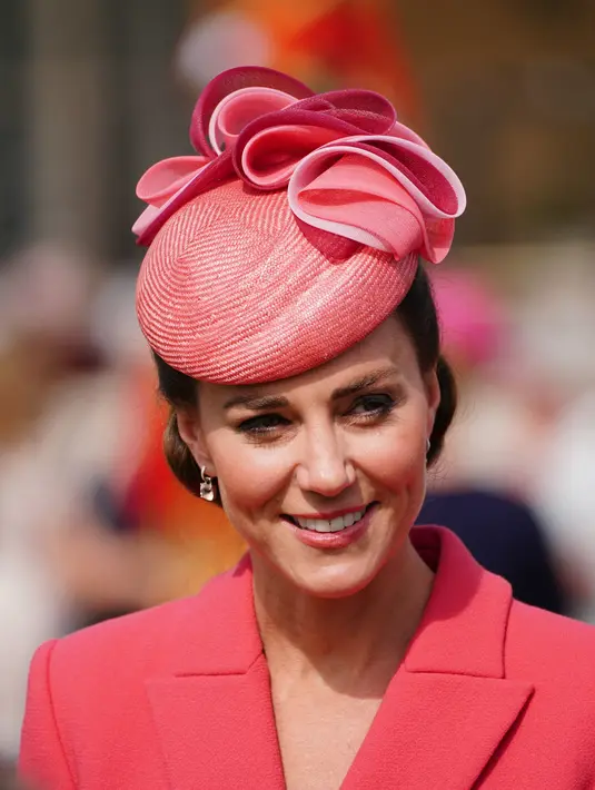 Kate Middleton, Duchess of Cambridge dari Inggris berbicara kepada para tamu di Pesta Taman Kerajaan di Istana Buckingham di London (18/5/2022). Kate Middleton tampak anggun dalam gaun mantel versi koral berwarna merah muda. (AFP/Pool/Dominic Lipinski)