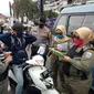 Petugas gabungan satpol pp, tni-polri menghentikan salah satu warga yang tidak menggunakan masker, dalam razia gabungan hari pertama penerapan aturan ketat penggunaan masker di Garut, Jawa Barat. (Liputan6.com/Jayadi Supriadin)