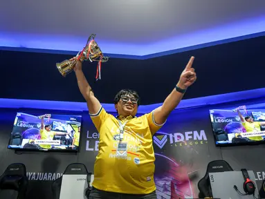 Atlet E-Sports Indonesia, Syamsul Arip mengangkat piala setelah menjuarai Lenovo Legion IDFM 2025 yang berlangsung di Sentinel Cyber Arena, Jakarta Timur, Minggu (23/02/2025). (Bola.com/Bagaskara Lazuardi)