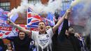 Para fans Glasgow Rangers menyalakan granat asap di luar Ibrox Stadium (7/3/2021) untuk merayakan keberhasilan tim kesayangan mereka merebut gelar Liga Utama Skotlandia setelah memimpin 20 poin dari saingan terdekat, Glasgow Celtic. (AFP/Andy Buchanan)