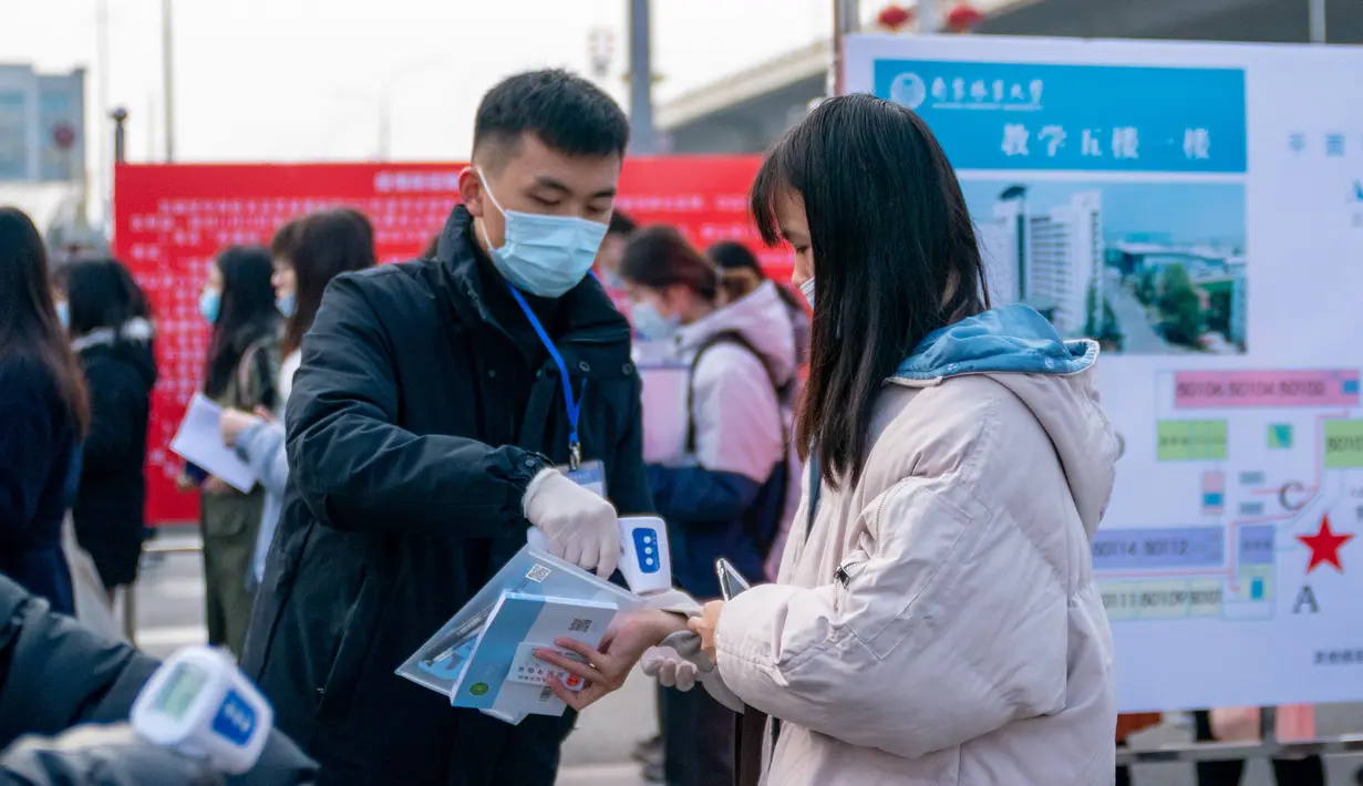Seorang staf memeriksa suhu tubuh calon peserta ujian pegawai negeri sipil (PNS) nasional China di sebuah universitas di Nanjing, Provinsi Jiangsu, China pada 29 November 2020. Ujian PNS nasional China untuk angkatan 2021 diadakan di seluruh penjuru negeri itu. (Xinhua/Du Yi)