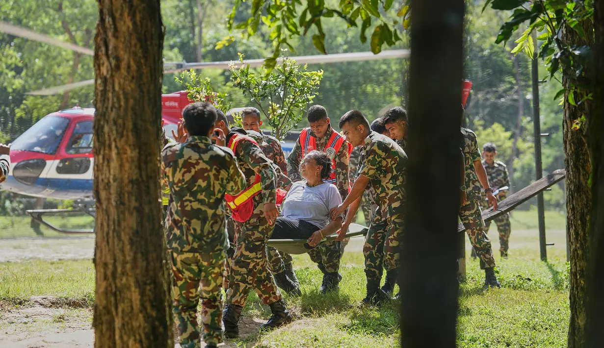 Tentara Nepal menggotong seorang lansia yang terluka setelah ia dievakuasi menggunakan helikopter dari wilayah yang terdampak banjir bandang di distrik Nuwakot, Nepal, Jumat, 28 Agustus 2026. (Foto AP/Rajesh Kumar Singh)