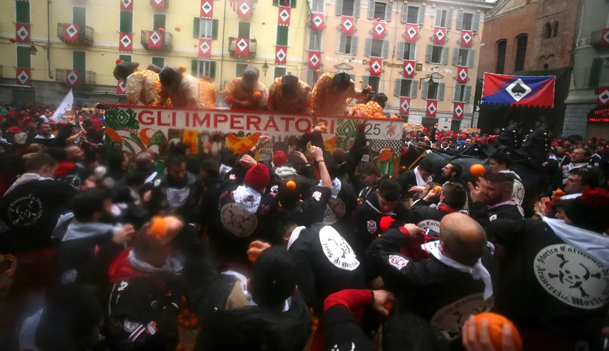 Sejumlah peserta saling lempar jeruk saat perang-perangan selama karnaval di kota Ivrea, Italia, Minggu (7/2). Peserta yang dibagi menjadi dua tim ini saling melempar jeruk menggunakan kostum dan aksesoris lengkap. (REUTERS/Stefano Rellandini)