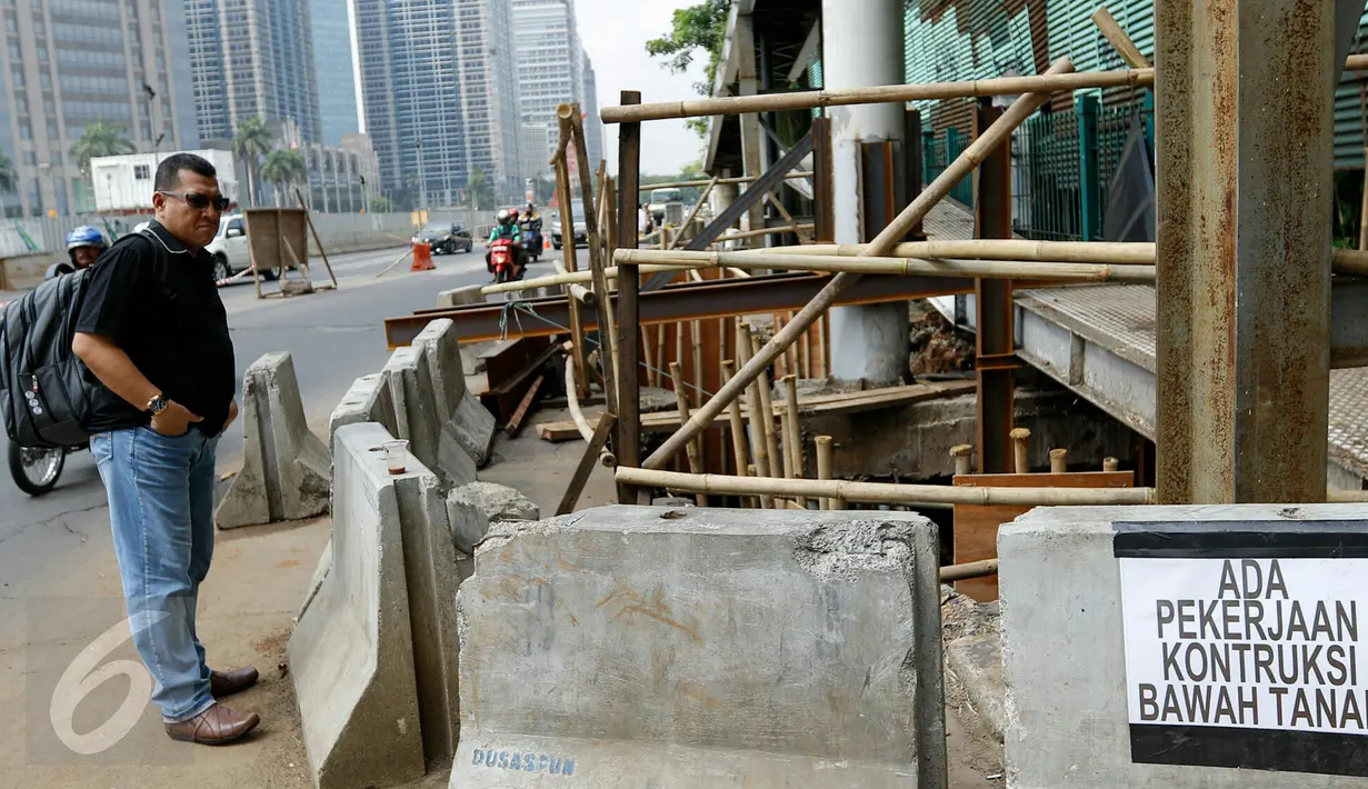 Warga berdiri di dekat pembongkaran struktur baja JPO sisi barat Polda Metro Jaya, di Jalan Jenderal Sudirman, Jakarta, Senin (23/11). Pembongkaran dilakukan karena pekerjaan konstruksi bawah tanah untuk perbaikan saluran air. (Liputan6.com/Yoppy Renato)