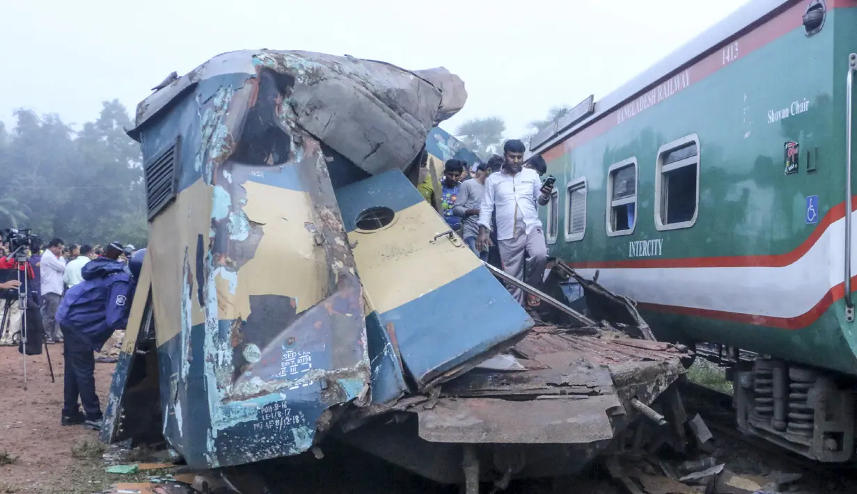 Orang-orang berdiri di gerbong kereta yang rusak parah setelah dua kereta yang melaju bertabrakan di distrik Brahmanbaria, 82 kilometer (51 mil) timur ibukota, Dhaka, Bangladesh, Selasa (12/11/2019). Sekitar 16 orang tewas dan 60 lainnya terluka akibat kecelakaan tersebut. (AFP Photo/STR)